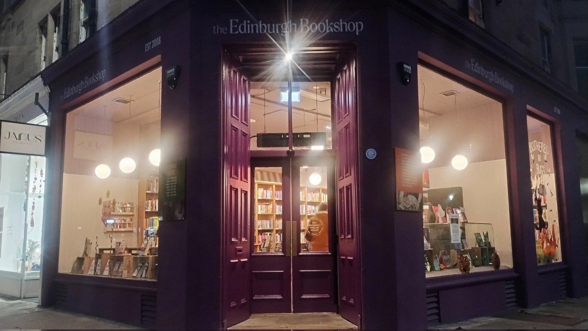 looking at the Edinburgh Bookshop doorway at night, the glass in the doors and the large windows on either side all glowing warmly with light inside, in contrast to the darkness outside, looking very inviting!