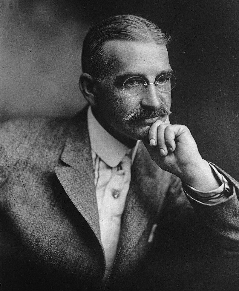 Copy of a portrait of L. Frank Baum, author of The Wonderful Wizard of Oz, c. 1911.

 George Steckel - Los Angeles Times photographic archive, UCLA Library.

Baum, who was in his mid-50s at the time, is depicted as a distinguished gentleman with neatly combed hair, a well-groomed mustache, and a thoughtful expression.

He is dressed in formal attire, likely a suit with a high-collared shirt and tie, reflecting the fashion of the early 20th century. 